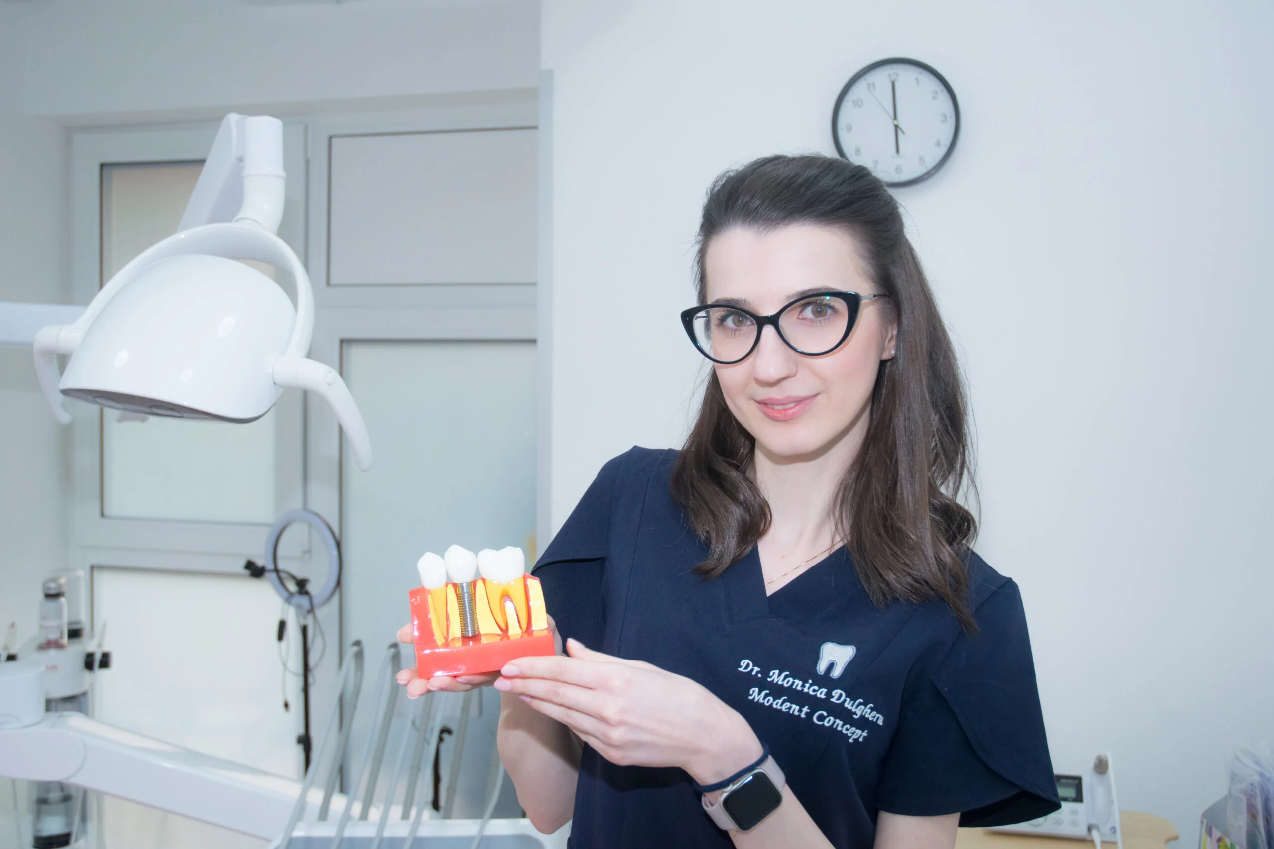 Medic protetician cu model de implant dentar, clinica stomatologica Cartierul Latin